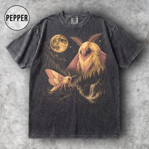 May include: A charcoal grey short-sleeve t-shirt featuring a graphic print of two moths in a forest landscape with a full moon and a waterfall. The design includes yellow and pink tones. The word PEPPER is printed in a circle in the top left corner.