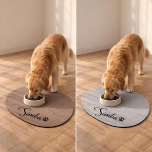May include: A golden retriever eating from a white bowl on a brown oval pet feeding mat. The mat has the name "Simba" in cursive with a paw print. The dog is standing on a wooden floor.