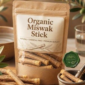 May include: A brown paper pouch labeled Organic Miswak Stick containing several wooden sticks with fibrous ends. The pouch features the text Natural, Chemical Free, Premium Quality and a green 100% Organic seal. Loose sticks lie on a wooden board.