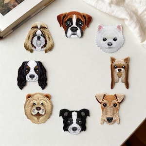 Może przedstawiać: Haftowane naszywki przedstawiające różne rasy psów, w tym boksera, shih tzu i cavalier king charles spaniel. Każda naszywka prezentuje szczegółowe rysy twarzy i faktury sierści, w różnych kolorach.