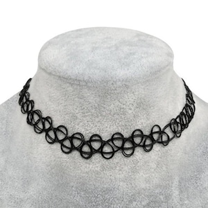 Może przedstawiać: Czarny naszyjnik typu choker z powtarzającym się wzorem splecionych kółek. Projekt składa się z cienkich, elastycznych żyłek splecionych w serię ciągłych pętli, tworzących delikatną, ażurową strukturę wokół obszaru szyi.