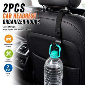 May include: A black plastic car headrest organizer hook with an adjustable nylon strap attached to a vehicle seat. The hook supports a clear plastic water bottle with a teal cap. Text on the image reads 2PCS CAR HEADREST ORGANIZER HOOKS.