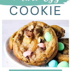 Op de afbeelding: Close-up van een Mini Egg Cookie op een wit bord. De koek is goudbruin en bezaaid met chocolade chips en pastelkleurige snoepeieren. De afbeelding bevat de tekst "Mini Egg Cookie" en "Get the Recipe".