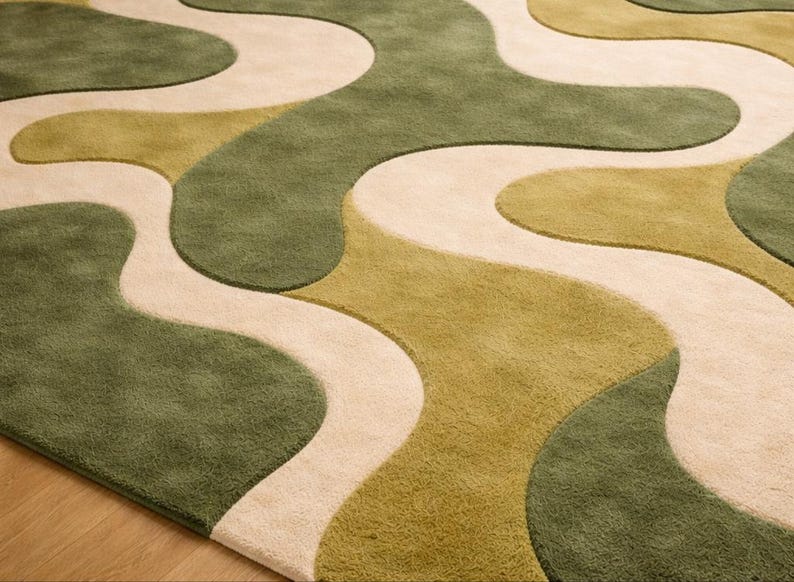 May include: A close-up of a rug with a flowing, abstract design. The rug features a pattern of interconnected, organic shapes in shades of green and beige. The rug's texture appears soft and plush, suitable for home decor.