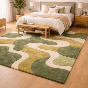 May include: A green, beige, and olive-colored area rug with a wavy, abstract design. The rug is placed in a bedroom setting, complementing the wooden furniture and neutral-toned bedding. The rug's pattern adds a modern touch to the room's decor.