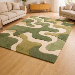 May include: A large, rectangular area rug with a flowing, abstract design in shades of green and beige. The rug features a wavy pattern, creating a modern and organic aesthetic. It is placed on a hardwood floor in a living room setting.