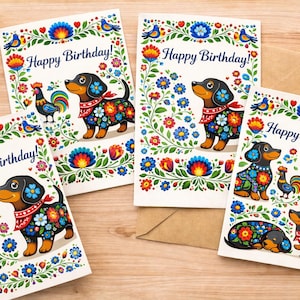 Può includere: Quattro biglietti di auguri con un design di arte popolare. Ogni biglietto presenta un cane bassotto con motivi floreali, un gallo e la scritta "Happy Birthday!". I biglietti sono circondati da illustrazioni floreali e di uccelli.