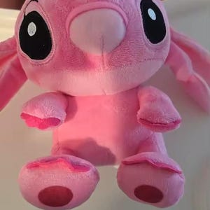 Puede incluir: Un peluche rosa con grandes ojos negros, orejas largas y una nariz peque&ntilde;a. El juguete tiene un cuerpo redondo, brazos peque&ntilde;os y pies grandes. El juguete es un personaje de una popular pel&iacute;cula de animaci&oacute;n.