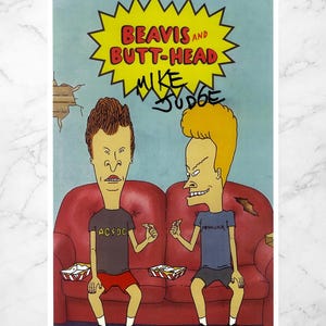 May include: A print featuring the animated characters Beavis and Butt-Head, seated on a red sofa. The image includes the text "BEAVIS and BUTT-HEAD" in a yellow burst, with the signature "MIKE JUDGE". The characters are wearing band t-shirts.