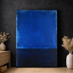 Puede incluir: Gran pintura abstracta con una combinación de dos colores. La parte superior es azul vibrante, que transiciona a un azul marino oscuro en la parte inferior. La obra de arte se exhibe en una pared oscura, creando un contraste llamativo.