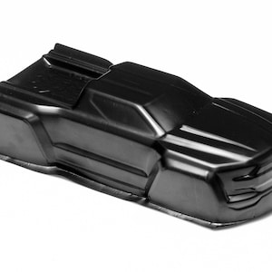 Peut inclure: Coque de carrosserie de voiture en plastique noir brillant, conçue pour un véhicule télécommandé. La coque présente une forme profilée avec des détails moulés, dont une calandre avant et un aileron arrière. La carrosserie mesure environ 30 cm de long.
