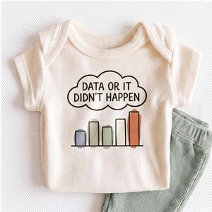 May include: A cream-colored ribbed baby bodysuit featuring a black cloud graphic with the text "DATA OR IT DIDN'T HAPPEN" and a bar chart below with five vertical bars in blue, beige, green, white, and orange, paired with sage green ribbed pants.
