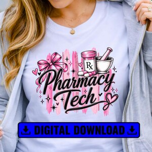 May include: A light blue t-shirt featuring a graphic design with the text Pharmacy Tech in black script. The design includes a pink bow, a prescription bottle with an Rx label, a mortar and pestle, pink hearts, and pink brush strokes.