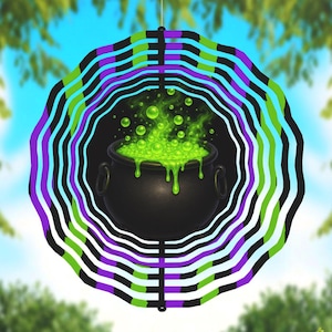 May include: A Halloween wind spinner with a black cauldron filled with bubbling green liquid. The cauldron is at the centre of a circular design with alternating black, purple, green, and blue stripes. The background shows a blurred view of trees and sky.