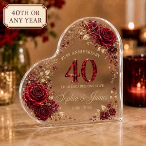 May include: A heart-shaped clear acrylic plaque featuring a red rose and gold leaf floral design. The text reads: Ruby Anniversary, 40, Four Decades, One Love, Sophia & James, 1986-2026. A separate rectangular sign above reads: 40th or any year.