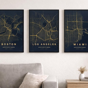 Puede incluir: Tres impresiones enmarcadas de mapas de ciudades. Los mapas presentan diseños de calles doradas sobre un fondo azul oscuro. Las ciudades que se muestran son Boston, Los Ángeles y Miami. Cada impresión está etiquetada con el nombre de la ciudad y los Estados Unidos de América.