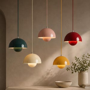 Puede incluir: Cinco lámparas colgantes en forma de cúpula suspendidas a diferentes alturas. Las lámparas presentan un diseño de dos partes con una cúpula superior grande y una inferior más pequeña en verde oscuro, crema, rosa claro, amarillo y rojo.