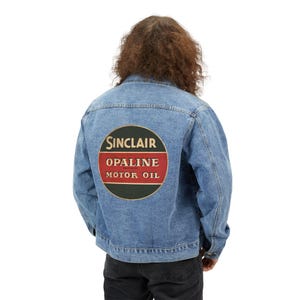 May include: A light blue denim jacket with a large Sinclair Opaline Motor Oil patch on the back. The patch is a circular design with a red and white stripe and the words "SINCLAIR", "OPALINE", and "MOTOR OIL" in white lettering.