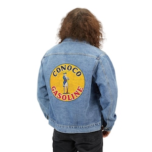 May include: A light blue denim jacket with a large, circular Conoco Gasoline logo on the back. The logo features a yellow background with a colonial-era figure and the words "CONOCO GASOLINE".