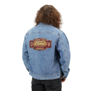 May include: A light blue denim jacket with a classic design. The back of the jacket features a rectangular patch with the words "GENUINE FORD PARTS & ACCESSORIES AUTHORIZED DISTRIBUTOR" in a vintage style.