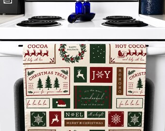 Op de afbeelding: Een kerstkeukendoek met een crèmekleurige achtergrond en diverse rode en groene vakantieontwerpen. De handdoek bevat teksten als "COCOA", "CHRISTMAS TREES" en "MERRY CHRISTMAS", samen met feestelijke illustraties.