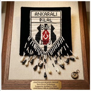 May include: Framed beaded badge with the text "ANKARALI BILAL BUK" in black and white. The badge has a black background and a decorative fringe. A small compass is in the lower right corner. The frame is wood.