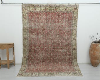 Puede incluir: Una alfombra rectangular grande que presenta un campo central de color rojo descolorido con intrincados patrones florales y un borde ancho de color beige claro decorado con motivos botánicos repetitivos en tonos rojos y verdes apagados.