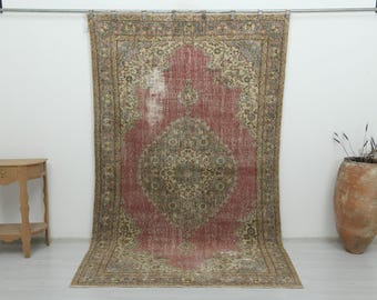 Puede incluir: Una alfombra rectangular grande con un diseño de medallón central en tonos apagados de rosa viejo, beige y verde salvia. La alfombra tiene un borde ancho e intrincado con motivos florales y una textura desgastada en toda la superficie.