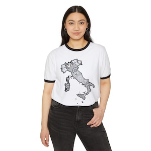 May include: White ringer t-shirt with a black collar and sleeves. The shirt features a detailed black and white graphic of the Italian peninsula, with the Italian flag at the top. The shirt is worn by a person.