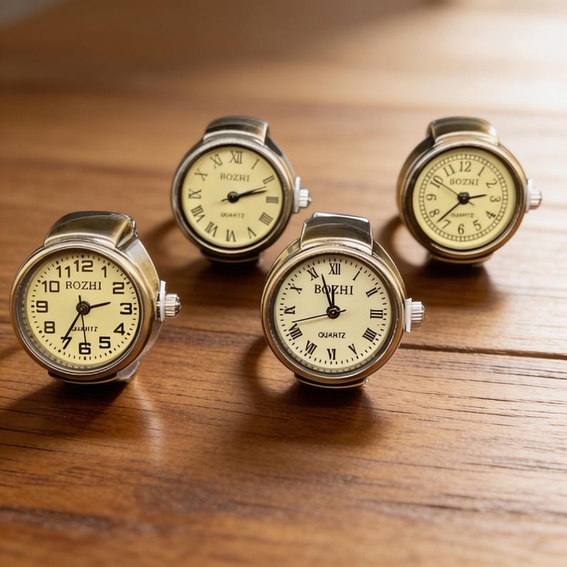 May include: Four antique-style ring watches with cream-colored faces and black Roman numeral hour markers. The watch faces display the brand name "ROZHI" or "BOZHI". The rings have a metallic finish and are set on a wooden surface.