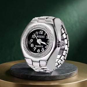 May include: A silver ring watch with a black face and white numerals. The watch face displays the brand name "BOZHI" and the word "QUARTZ". The band is made of interlocking metal links.