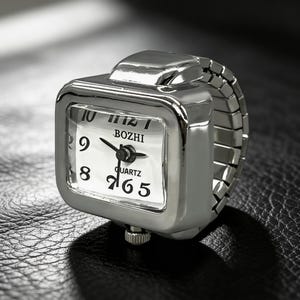 May include: A silver-toned ring watch with a square face and an elastic band. The watch face is white with black numerals and hands, and the brand name "BOZHI" is visible. The watch is a unique accessory.