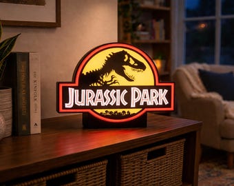 May include: Illuminated "Jurassic Park" sign featuring the iconic logo with a T-Rex silhouette and the film's title in white lettering. The sign has a black base and a yellow and red illuminated background. Perfect for movie fans.