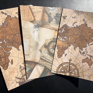 May include: Four vintage-style notebooks with a world map design. The notebooks feature a brown and beige color scheme with a compass and sailing ship illustration. The pages have a distressed, aged appearance.