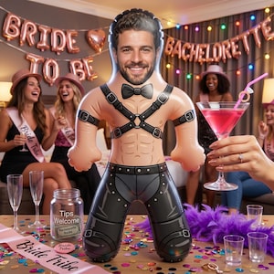 Op de afbeelding: Een opblaasbare pop met een mannelijk gezicht, met een zwarte vlinderdas, harnas en broek. De pop is een novelty-item voor een vrijgezellenfeest, met de woorden "Bride to Be" en "Bachelorette" op de achtergrond.