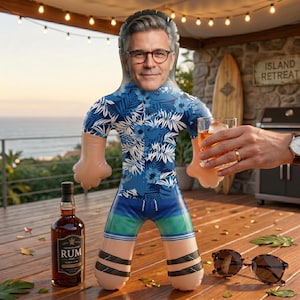 Op de afbeelding: Een opblaasbare figuur met een mannengezicht, gekleed in een blauw bloemenhemd en korte broek, met een glas amberkleurige vloeistof. Een fles rum en een zonnebril liggen op een houten oppervlak. De scène speelt zich buiten af.