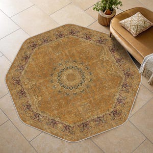 May include: An octagonal area rug featuring a central medallion with dark blue and cream floral patterns on a mustard yellow background. The border displays intricate maroon and cream motifs, with a white edge finish throughout the entire rug.