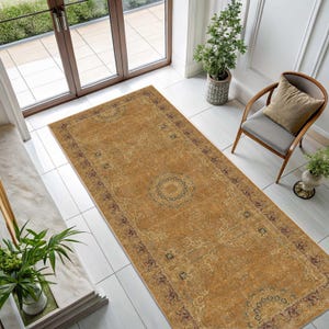 May include: A rectangular area rug featuring a distressed mustard yellow field with a central circular medallion and intricate dark red and blue floral border patterns. The rug displays a faded, worn texture across its surface.