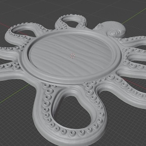 May include: A light gray, circular tray featuring a central flat surface surrounded by eight radiating octopus tentacles. Each tentacle is detailed with a series of small, raised circular suction cups along the inner edge of the arm.