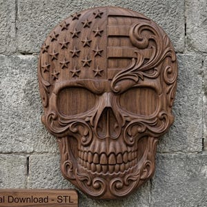 May include: A dark brown wooden wall carving of a human skull featuring an American flag pattern on the left side with stars and stripes, and intricate scrollwork filigree detailing on the right side and around the jawline and eye sockets.