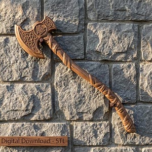 May include: A carved wooden axe featuring intricate Celtic knotwork patterns on the blade and a textured, wrapped handle design. The axe head displays a central Valknut symbol. A small rectangular plaque below reads Digital Download - STL.