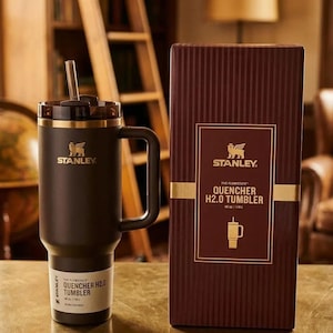 May include: A black Stanley Quencher H2.0 tumbler with a handle and a straw, next to its brown box. The box features the Stanley logo and product details. The tumbler is 40 oz / 1.18 L.