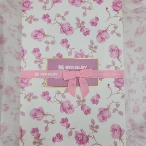 May include: A rectangular gift box with a floral rose pattern in pink and white. The box is wrapped with a pink ribbon and bow. The brand name "STANLEY" is visible on the box.