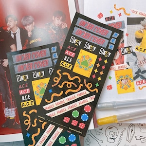 May include: A set of stickers featuring a black and yellow design with the words "Undercover" and "Okay" repeated. The stickers also feature a playing card with a spade, dice, and the word "A.C.E." repeated. The stickers are on a white background.
