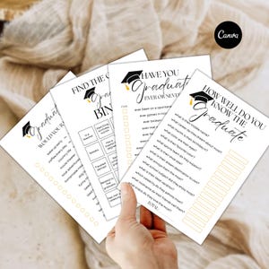 May include: Four white paper game sheets with graduation-themed text and graphics. The sheets include phrases like "Would You Rather," "Find the Graduate Bingo," and "How Well Do You Know the Graduate?" A hand holds the sheets.