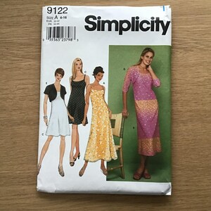 May include: A Simplicity sewing pattern envelope, number 9122, size A 6-16. The front displays illustrations of four different dress styles, including a light blue dress with a black bolero, a black dress, a yellow floral dress, and a pink ombre dress.