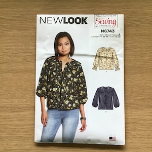 May include: A sewing pattern for a blouse with a ruffled collar. The pattern includes three different views: a black and white floral print, a cream and pink floral print, and a solid blue. The pattern is for sizes US 8-20, FR 36-48, and Euro 34-46. The pattern is produced in partnership with Love Sewing.
