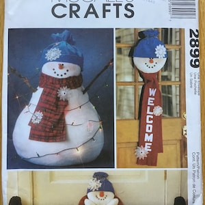 May include: McCall's Crafts pattern 2899 envelope featuring illustrations of three snowman-themed fabric projects. The designs include a large snowman, a hanging door decoration with the word WELCOME, and a long draft stopper.