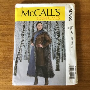 May include: McCall's Costumes sewing pattern M7855. The pattern features a woman wearing a brown leather coat with a fur trim and a blue scarf. The background shows a snowy forest scene. Size A5 (6-8-10-12-14).