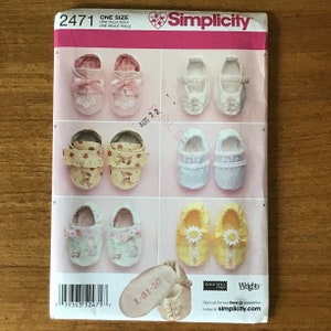 May include: Simplicity pattern 2471 for baby shoes. The pattern features various shoe designs, including those with bows, straps, and floral accents. The pattern includes the text "ONE SIZE" and the date "AUG 22".